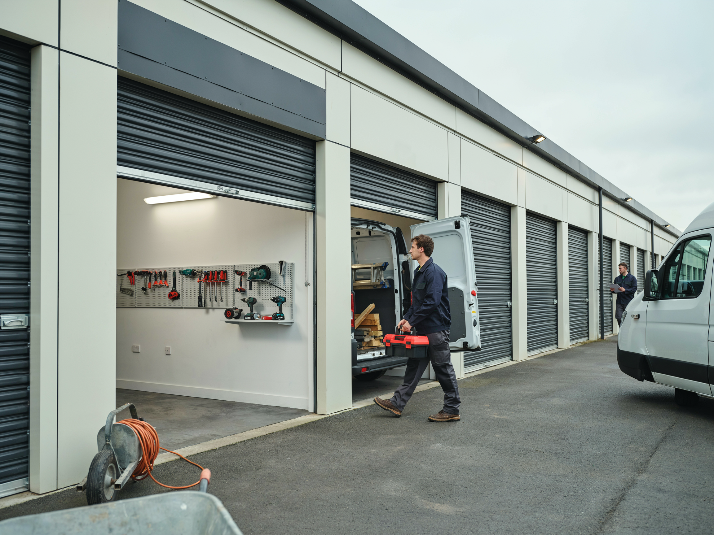 Tradesperson loading tools from a unit, van alongside